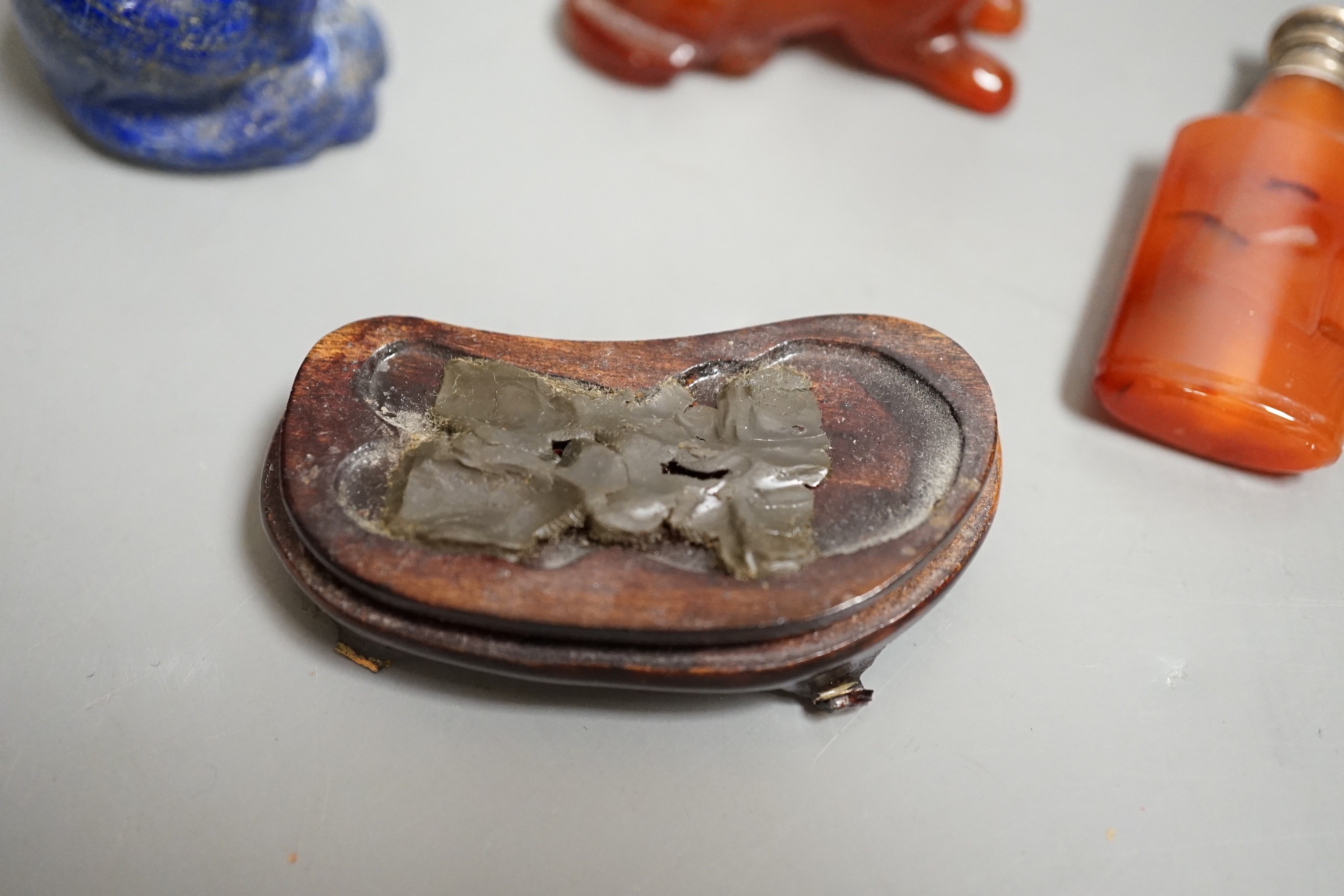 A Chinese carved lapis lazuli seated cat, a banded agate recumbent cat on hardwood stand and a white metal mounted agate scent bottle